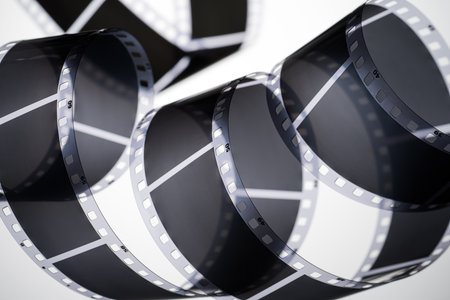 A close-up of a coiled black and white 35mm photographic film strip with blank frames.