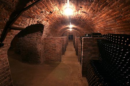 Vintage wine bottles stacked in the old cellar of the winery
