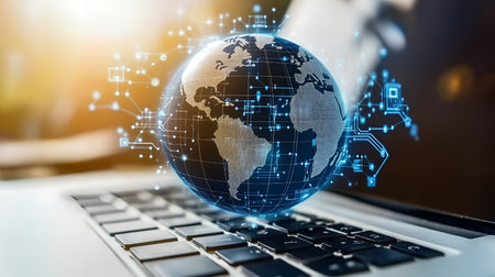 A digital globe hovers over a laptop keyboard, representing global connectivity.の素材