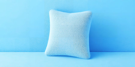 A soft light blue textured pillow sits centered against a solid blue background. Clear details and...の素材