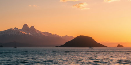 A breathtaking sunset over the water with mountains in the background.の素材