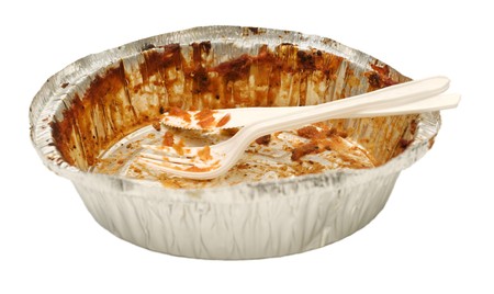 Plastic white knife and fork sitting in an aluminum tray take out tray emptied of its food contents. の写真素材