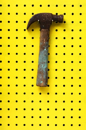 Old hammer with paint marks hangs from metal hook. Wooden handle with metal head.の写真素材