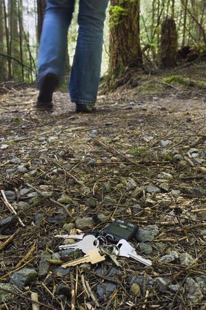 A set of house and car keys lay on the forest floor as a person walks away.の写真素材