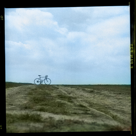 vintage bike on a horizon with sky old photograph with authentic film grainの写真素材
