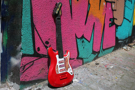 guitar leaning against a colored wallの写真素材