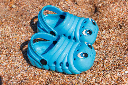 Blue children's sneakers on the beach