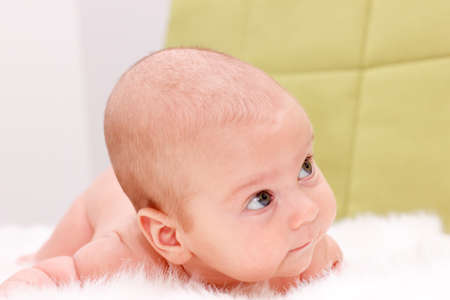 Baby lying on a white furの写真素材