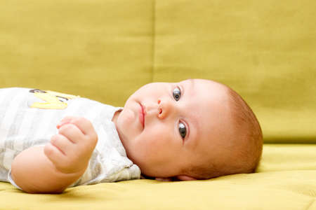 Baby lying on the green couch serious lookの写真素材