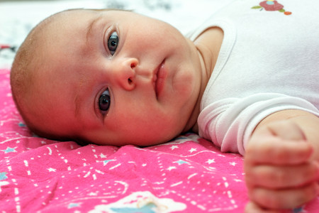 cute baby boy lying and looking into the camera on the violet background