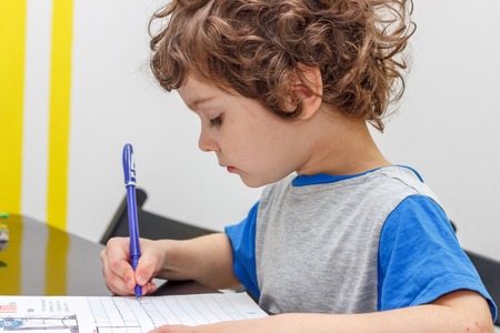 the lovely curly-headed boy writes copy-books, lettersの写真素材