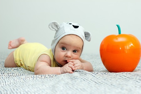 Kid in a cap with ears gnaws a hand. Red appleの写真素材