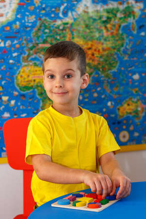 Kid playing with wooden colorful puzzle, education concept.