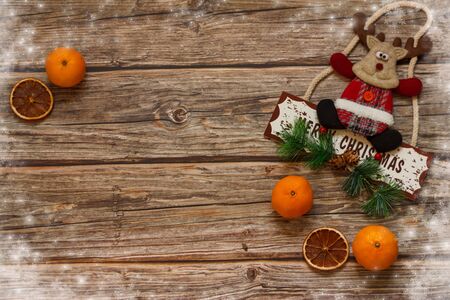 Wooden background with mandarines and Christmas deer inside the christmas hat on the table. Winter holiday frame. Flat lay top view. copy spaceの写真素材