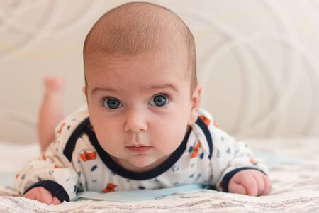 portrait of 2 months old adorable baby boy with big blue eyes and long eyelashes. cute baby lying on...