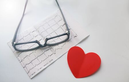 Cardiogram chart with glasses and red heart on table closeupの写真素材