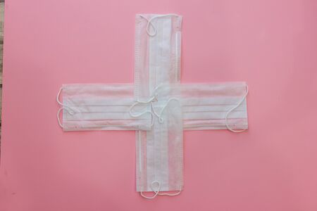 White cross shaped Medical masks on pink background