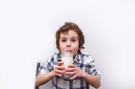 joyful boy with a glass of milk on white background. Source of calcium. Concept of lactose deficiencyの写真素材