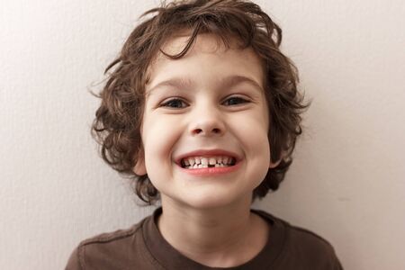 Charming curly boy smiles. The boy lost the first milk tooth