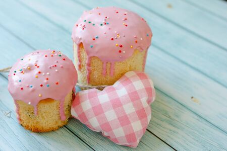 Sweet pink cake dessert and pink heart on blue wooden background. View on top, copy space.