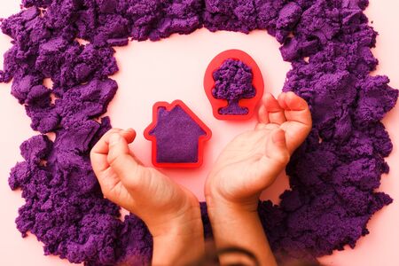 hands little kid mold house and tree, playing with kinetic sand. the development of fine motor skills. educational games.の写真素材