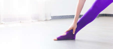 sportswear stretch legs on white floor in sunny gym studioの写真素材