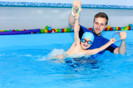 Coach teaches the baby to swim in the pool. baby splash in the water in the pool