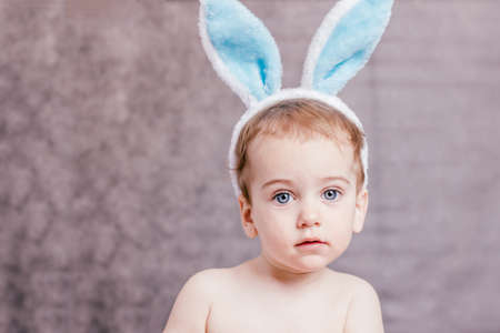 Cute baby in a blue bunny ears on gray backgroundの写真素材