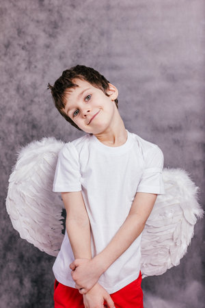 A child wearing angel wings and looking upwards on gray backgroundの写真素材