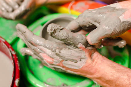 A close-up of a potters hand creates a clay bowl on a potters wheel. pottery training