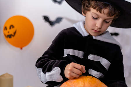Children in Halloween costumes paint pumpkins. Boy decorate the house for holiday. Celebrating at home concept.の写真素材