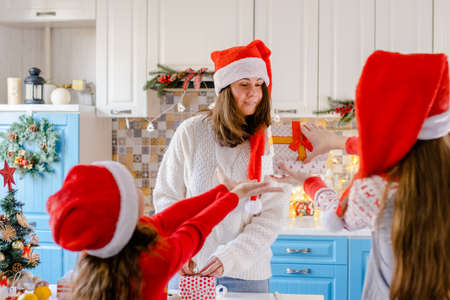 Children in Santa hats give a gift to their motherの写真素材