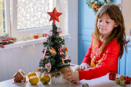 Happy child decorating Christmas tree at homeの写真素材