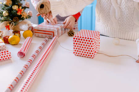 Cropped Woman packs Christmas gifts, cuts packing paper with scissorsの写真素材