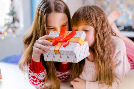 Christmas Child Girl opening Box in kitchen. Indoor Lightsの写真素材