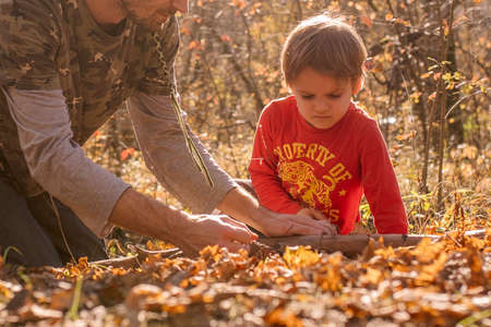 father and son saw a log with a wire saw in camp autumn, spending time togetherの写真素材