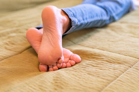 crossed bare kid legs on green sofa