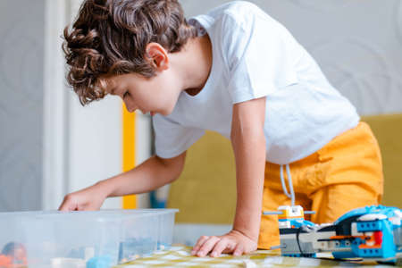 Kid collects robot from plastics details and programmed on tablet, robotics.の写真素材