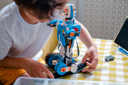 Kid collects robot from plastics details and programmed on tablet, robotics.