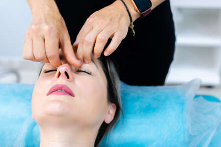 unidentified young woman masseur doing facial massage to young client womanの写真素材