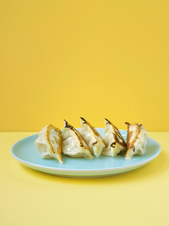 Chinese steamed dumplings on a blue plate with yellow backgroundの素材