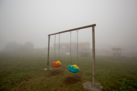 Children's playground in a foggy morning. Children's swing.の写真素材
