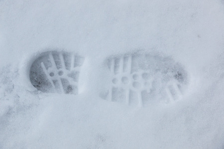 Foot print of a human shoe on the white snowの写真素材