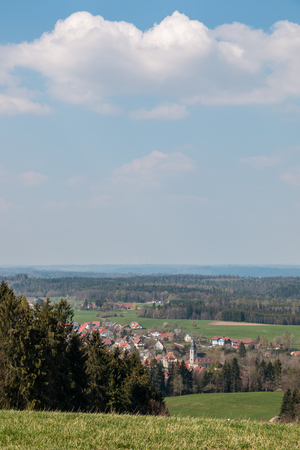 Little village in the middle of the german countryside with hills, forests, fields and meadowsの写真素材