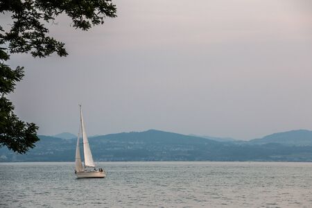 Sailboat with white sails on the lake
