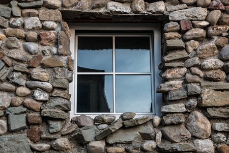 Natural stone wall with colorful and different sized stones and windowの写真素材