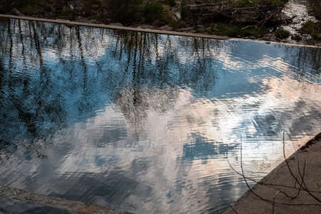 Reflections in the water of the cloudy sky near the damの写真素材