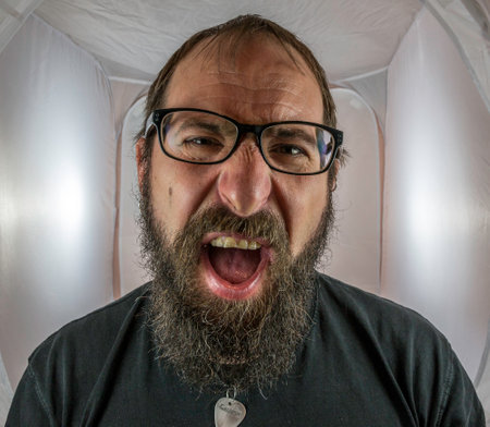 A bearded, shouting and angry looking man with black glassesの写真素材