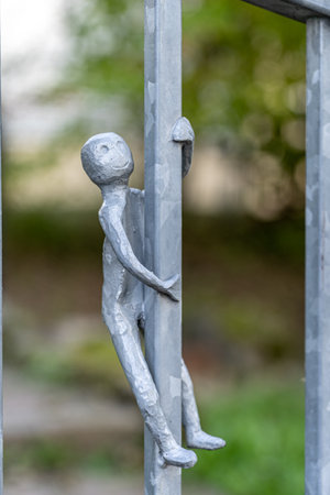 Little figures made of steel on a metal fence in shape of playing kidsの写真素材