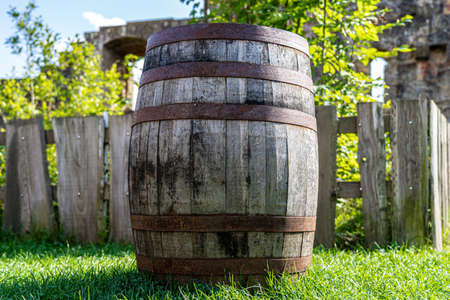 Big wooden wine cask with rusted barrel hoops on the green grassの写真素材